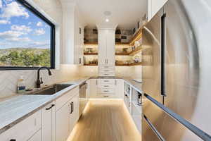 Kitchen with stainless steel appliances, open shelves, decorative backsplash, and white cabinets