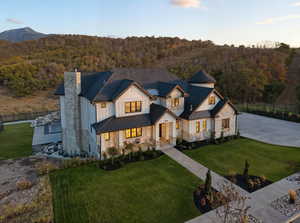 Modern inspired farmhouse featuring a standing seam roof, a metal roof, stone siding, a forest view, and driveway