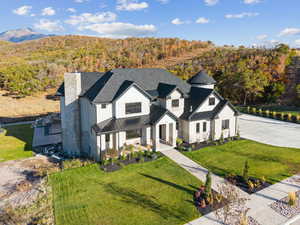 View of front of home with a standing seam roof, a metal roof, a front yard, a wooded view, and a chimney