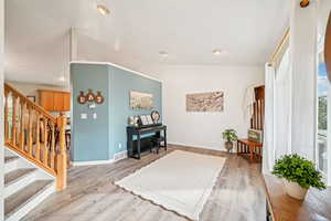 Interior space featuring vaulted ceiling, stairs, light wood-style floors, and recessed lighting