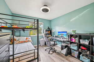 Bedroom featuring light wood-type flooring, a desk, and a textured ceiling
