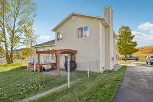 Rear view of house featuring a patio area, a chimney, and a pergola