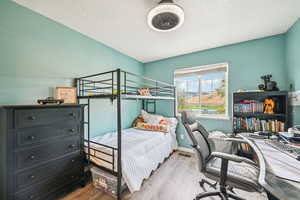 Bedroom with light wood-style floors, a textured ceiling, and an office area