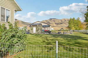 Fenced yard featuring an outdoor structure, a mountain view, and a patio area. Mountain, and rural views
