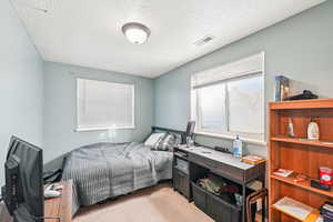 Bedroom featuring light carpet and a textured ceiling