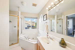 Full bath featuring vanity, a stall shower, and a whirlpool tub