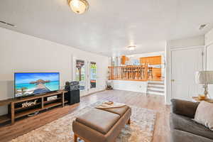 Living area featuring a textured ceiling, light wood-style floors, and stairs