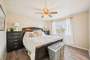 Bedroom with a ceiling fan, wood finished floors, and a textured ceiling