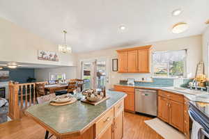 Kitchen with light wood-type flooring, stainless steel appliances, a kitchen island, pendant lighting, and open floor plan
