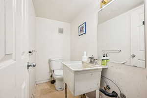 Half bathroom with a textured ceiling and vanity