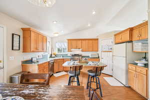 Kitchen with a kitchen breakfast bar, lofted ceiling, light wood-style flooring, appliances with stainless steel finishes, and light countertops