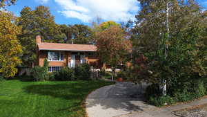 View of front of home with a front lawn, brick siding, and a chimney