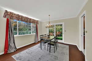 Dining space with ornamental molding, a chandelier, and dark wood finished floors