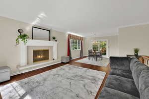 Living area with a high end fireplace, ornamental molding, and wood finished floors