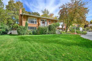 Bi-level home with brick siding, a front yard, and a chimney