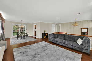 Living area with a chandelier, crown molding, dark wood-type flooring, recessed lighting, and wallpapered walls