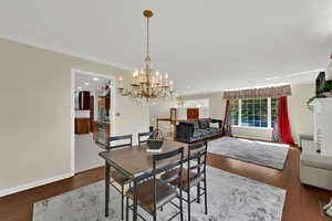 Dining space with wood finished floors, a chandelier, and ornamental molding