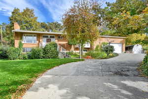 Bi-level home with a front yard, brick siding, driveway, and a chimney