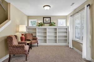 Living area featuring light colored carpet and baseboards