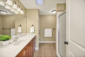 Full bath with light tile patterned floors, vanity, and a stall shower