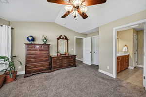 Bedroom with light carpet, lofted ceiling, ensuite bath, a ceiling fan, and light tile patterned floors