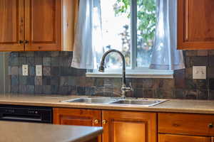 Kitchen with tasteful backsplash, brown cabinetry, and plenty of natural light