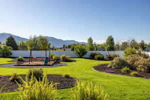 Fenced backyard featuring a playground and a mountain view