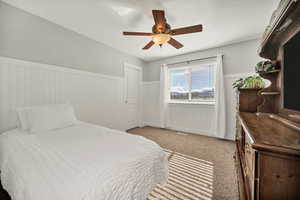 Bedroom with wainscoting, light carpet, and ceiling fan