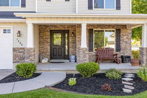 Entrance to property featuring stone siding and covered porch