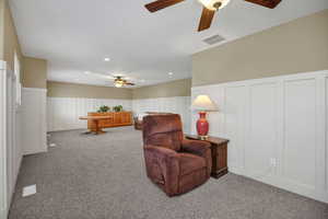 Living area with a decorative wall, a wainscoted wall, a ceiling fan, carpet flooring, and recessed lighting