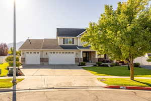 View of front facade with a front yard, driveway, an attached garage, and brick siding