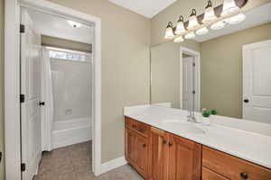 Bathroom featuring vanity, shower / bath combo with shower curtain, and light tile patterned floors