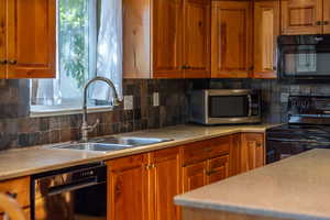 Kitchen featuring black appliances, backsplash, brown cabinets, and light countertops