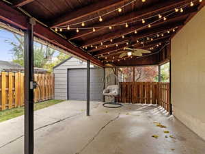 View of patio featuring a garage, an outbuilding, and ceiling fan