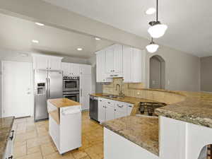 Kitchen with pendant lighting, appliances with stainless steel finishes, a peninsula, white cabinetry, and recessed lighting