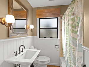 Bathroom featuring shower / bath combination with curtain and a wainscoted wall