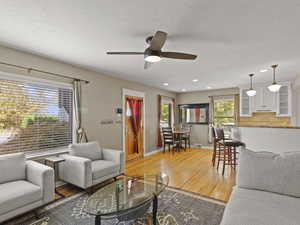 Living area with light wood flooring, ceiling fan, and recessed lighting