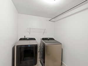 Washroom featuring a textured ceiling and independent washer and dryer