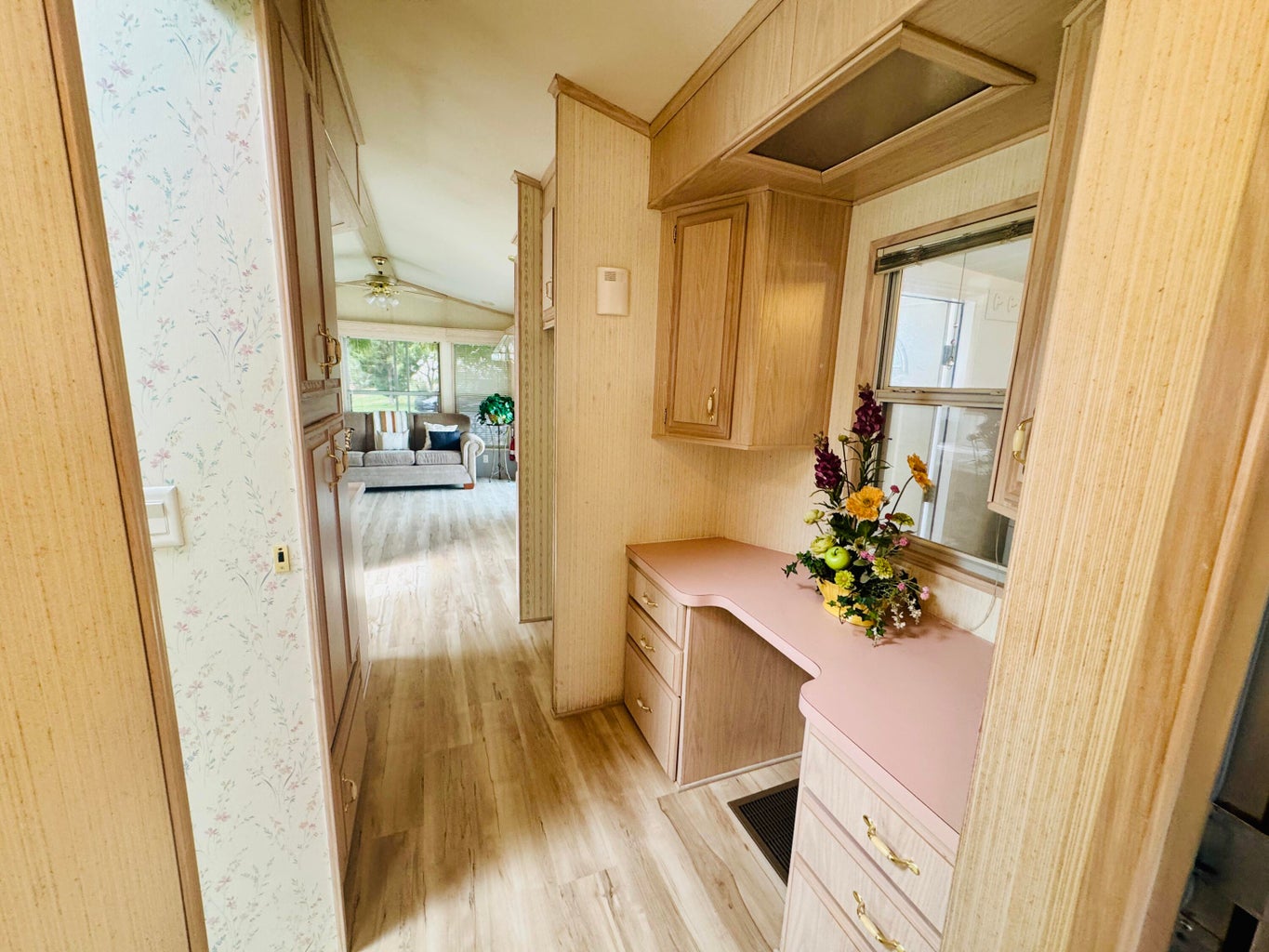 Hall with light wood finished floors, lofted ceiling, an office area, and wallpapered walls