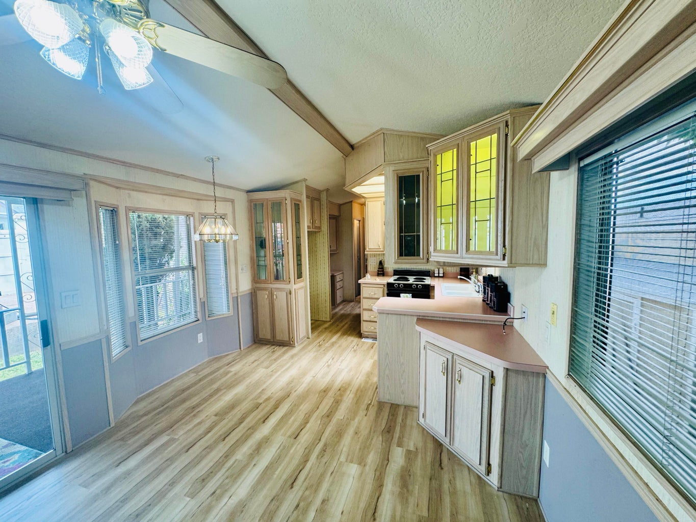 Kitchen featuring a chandelier, light countertops, light wood-style floors, glass insert cabinets, and hanging light fixtures