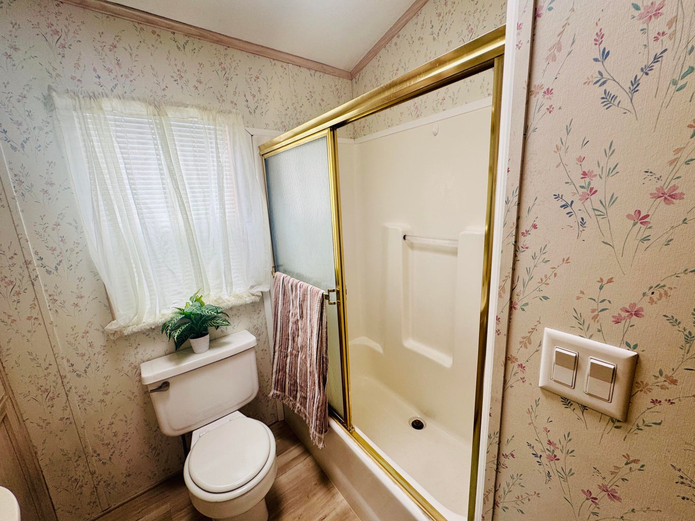 Bathroom featuring wallpapered walls, wood finished floors, and ornamental molding