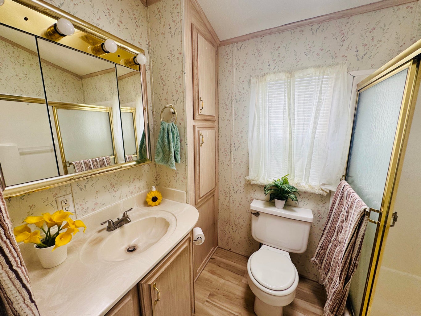 Bathroom with wallpapered walls, light wood-style flooring, vanity, and a stall shower