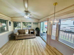 Sunroom / solarium with vaulted ceiling, wood finished floors, crown molding, and a chandelier