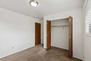 Unfurnished bedroom featuring dark carpet and a closet