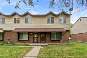 Traditional-style home featuring a front yard, covered porch, and brick siding