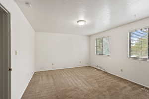 Empty room featuring carpet, a textured ceiling, and a smoke detector