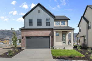 View of front of property with a garage, concrete driveway, a porch, brick siding, and a front yard