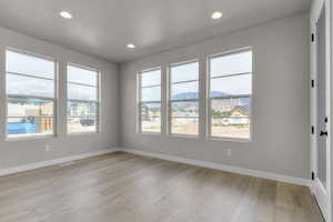 Empty room featuring a mountain view, recessed lighting, plenty of natural light, light wood-style flooring, and a residential view