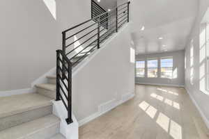 Staircase featuring wood finished floors, recessed lighting, and a high ceiling