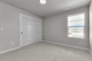 Unfurnished bedroom with light carpet, a closet, and a textured ceiling